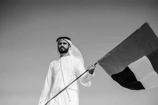 Orgulhoso homem Emirado árabe segurando uma bandeira dos Emirados Árabes Unidos no deserto . — Fotografia de Stock
