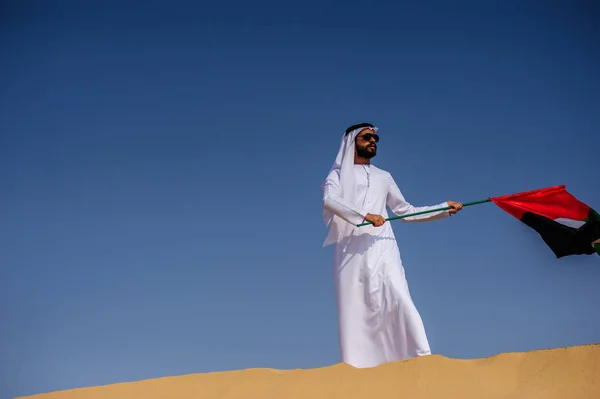 Gururlu Arap Emirlikleri adam çölde bir Birleşik Arap Emirlikleri bayrağı tutarak. — Stok fotoğraf