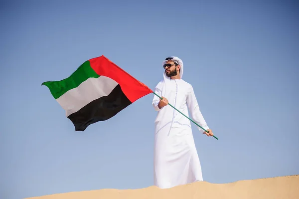 Orgulloso hombre árabe emiratí sosteniendo una bandera de los EAU en el desierto . — Foto de Stock