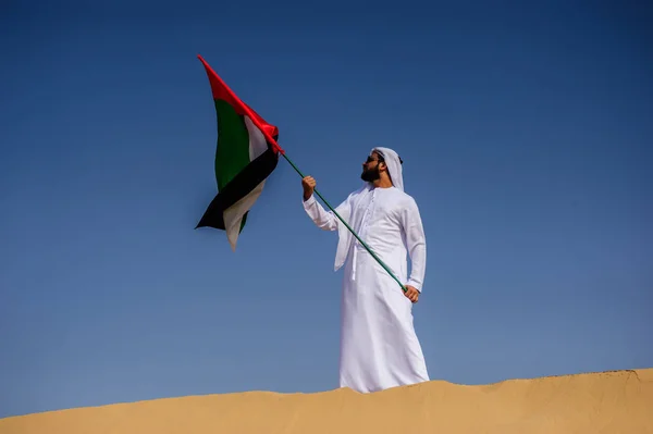 Stolt arabian Emirati man innehar en Uae flagga i öknen. — Stockfoto