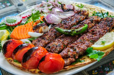 Sebzeli ve soslu sağlıklı barbekü. Siyah bir tabakla servis ediliyor. Işık arkaplanındaki görüntüyü kapat. Arapça yemek.