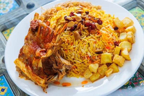 Plate of yellow rice topped with mutton meat and potatoes. — Stock Photo, Image