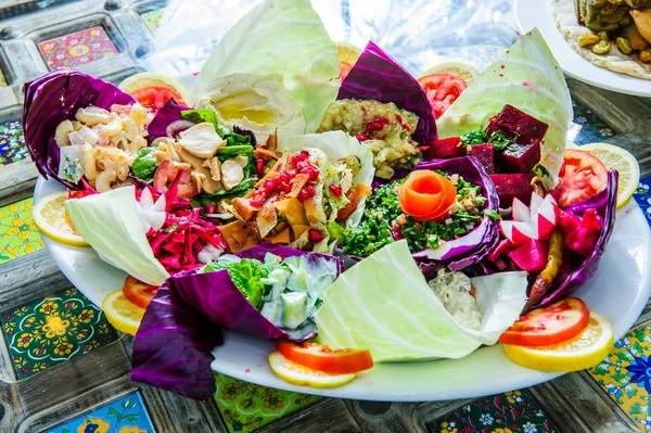 Vis met een salade in een bord wordt geserveerd op een tafel met een glas wortelsap. Het vrouwtje gaat lunchen.. — Stockfoto