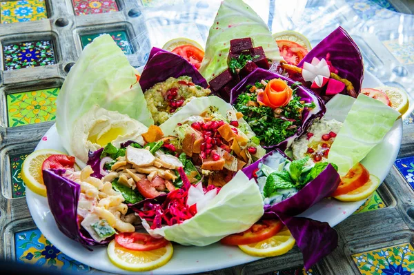 O peixe com uma salada em uma chapa serve-se em uma mesa com um copo de suco de cenoura. A fêmea está a almoçar . — Fotografia de Stock