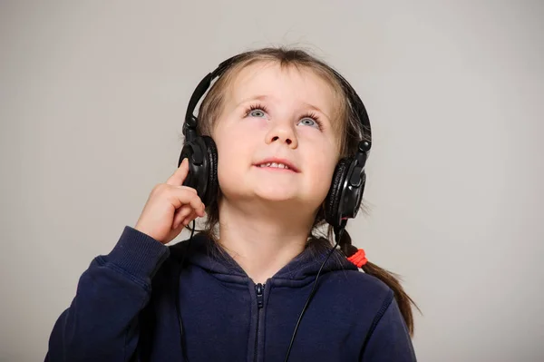 Smiling little girl with head phones on studio.