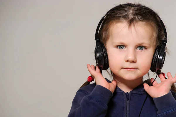 Smiling little girl with head phones on studio.