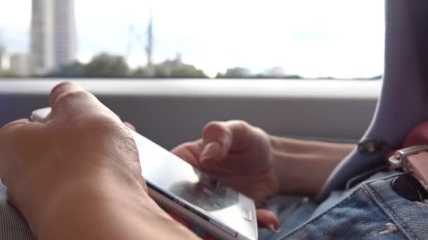 Flickan med sin smartphone i tåget. Att trycka på enhetens pekskärm. 4 k närbild video — Stockvideo