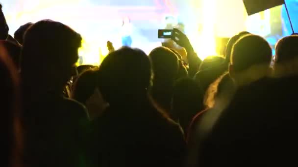 Audience of live show and bright stage flashes. Unrecognizable person shooting video with mobile phone. 4K shot — Stock Video