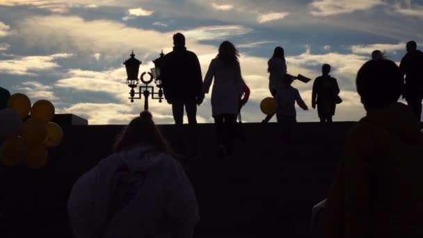 Siluetas de personas caminando arriba y abajo contra el cielo nocturno. Clip de cámara lenta — Vídeo de stock