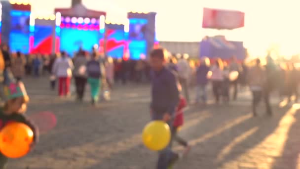 Rozmyte dzieci bawiące się z balonów na ulicy w godzinach wieczornych. Ciepłe kolory. 4 k tło bokeh strzał — Wideo stockowe