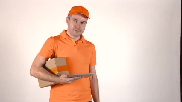 Zusteller in orangefarbener Uniform bedient seinen Tablet-PC und gibt dem Kunden ein Paket. grauer Hintergrund 4k isolierte Aufnahme — Stockvideo