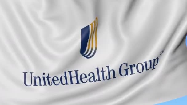 Zbliżenie macha flagą z logo Unitedhealth Group, Płynna pętla, niebieskie tło. Redakcji animacji. 4 k Prores, alfa — Wideo stockowe