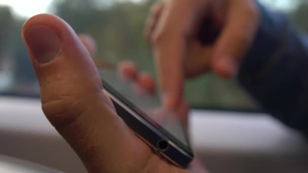 Man via zijn telefoon horizontaal tegen de trein raam. Scrollen en te tikken op een touchscreen van het apparaat. 4 k close-up video — Stockvideo