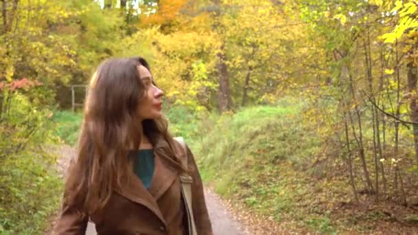 Menina morena feliz bonita andando através de florestas de outono. Close, 4K steadicam vídeo — Vídeo de Stock