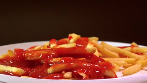 Multiple hands taking french fries and dipping them in tomato sauce. Fast food 4K timelapse against dark background — Stock Video