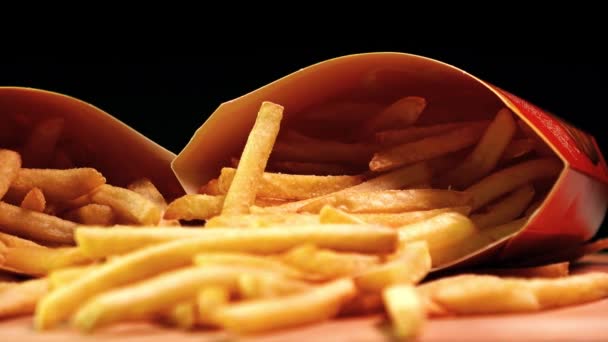 Shallow focus 4K closeup dolly shot of fast food paper boxes with french fries. Deep fried potato chips, junk food — Stock Video