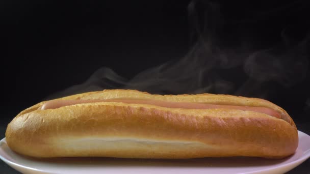 Stomen vers gemaakte hotdog tegen zwarte achtergrond. Wereldwijd populaire fastfood. 4 k close-up shot — Stockvideo