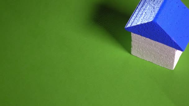 Makler platziert Spielzeughaus mit blauem Dach und kleinem Schlüssel vor grünem Hintergrund. Immobilienmarktkonzept. 4k-Video — Stockvideo