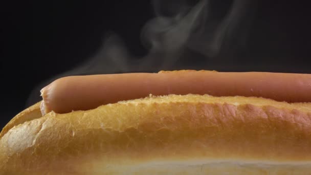 Freshly made hot dog against black background. Worldwide popular fast food. 4K close up dolly shot — Αρχείο Βίντεο