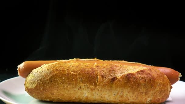 Cachorro quente recém-feito em vapor contra fundo preto. Popular fast food 4K closeup dolly vídeo — Vídeo de Stock