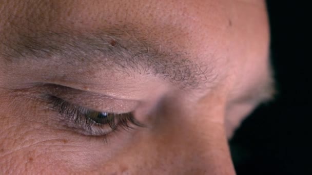 Очі серйозного кавказького чоловіка, який використовує свій планшетний комп'ютер, вид на профіль. Екран, що відображається в очах, пристрій освітлення світиться. 4K екстремальний крупним планом знімок — стокове відео