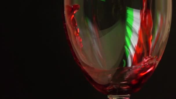 Verser du vin rouge dans un verre sur fond noir avec un drapeau italien en surbrillance. La vinification et les voyages en Italie concepts. Plan au ralenti super — Video