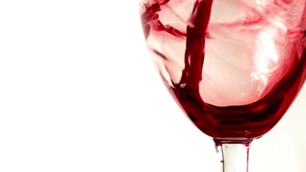 Kırmızı şarap kadehinin beyaz bir arka plana dayanır aşırı içine dökülür varlık kapatın. Şarap yapımı, koyu kırmızı renk ve lezzet kavramları. Süper ağır çekim vurdu — Stok video