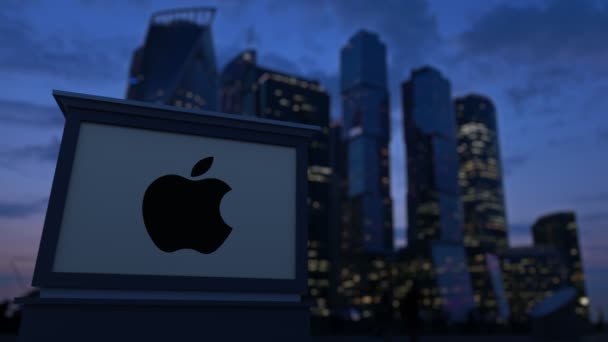 Cartelera con el logotipo de Apple Inc. en la noche. Rascacielos distritos de negocios borrosa fondo. Clip editorial 4K — Vídeos de Stock