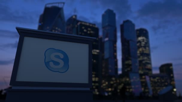 Papan nama jalan dengan logo Skype di malam hari. Blurred bisnis daerah pencakar langit latar belakang. Klip Editorial 4K — Stok Video