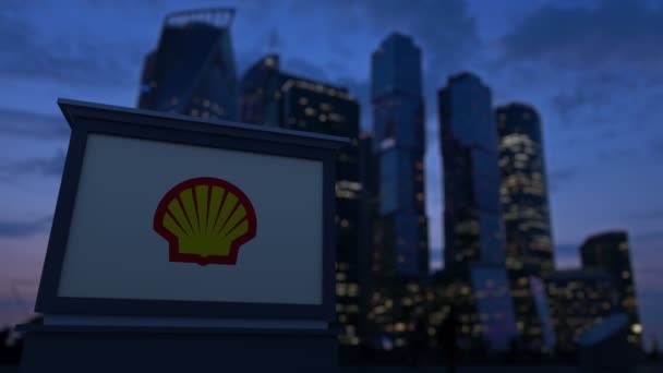 Skiltbord med Shell Oil Company-logo om kvelden. Tåkete forretningsdistrikts skyskrapere bakgrunn. Redaksjonell 4K-klemme – stockvideo