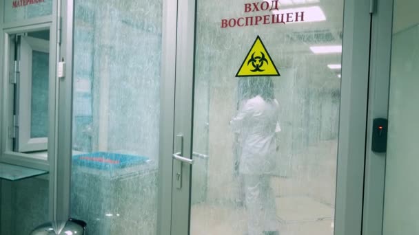 不可识别的实验室工作人员穿着白大衣离开医疗实验室与生物危害标志 4 k 视频 — 图库视频影像
