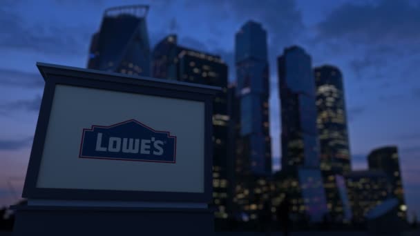 Gatan skyltar ombord med Lowes logotyp på kvällen. Suddig business district skyskrapor bakgrund. Redaktionella 4k klipp — Stockvideo