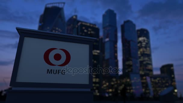 Placa de sinalização de rua com logotipo MUFG à noite. Desfocado arranha-céus distrito de negócios fundo. Editorial 4K clip — Vídeo de Stock