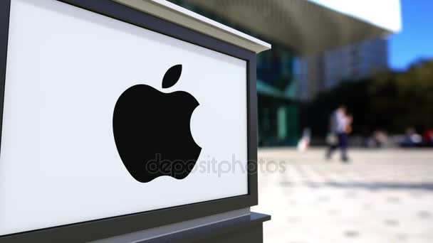Tablero de señalización con el logotipo de Apple Inc.. Centro de oficina borrosa y gente caminando fondo. Representación editorial 4K 3D — Vídeo de stock