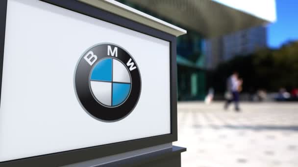 Tablero de señalización de calle con logotipo de BMW. Centro de oficina borrosa y gente caminando fondo. Representación editorial 4K 3D — Vídeos de Stock