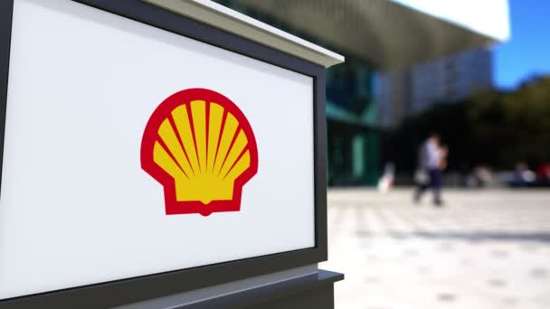 Cartelera con el logotipo de Shell Oil Company. Centro de oficina borrosa y gente caminando fondo. Representación editorial 4K 3D — Vídeo de stock