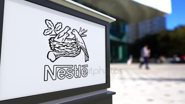 Oznakowanie ulicy deska z Nestle logo. Centrum biurowe niewyraźne i chodzenia osób tła. Redakcji 4k renderowania 3d — Wideo stockowe