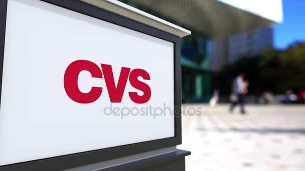 Tablero de señalización con logotipo CVS Health. Centro de oficina borrosa y gente caminando fondo. Representación editorial 4K 3D — Vídeo de stock