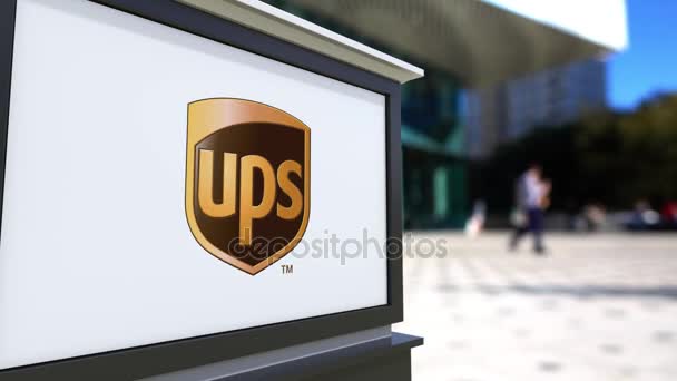 Panneau de signalisation routière avec logo UPS United Parcel Service. Centre de bureau flou et les gens de marche arrière-plan. Éditorial 4K rendu 3D — Video