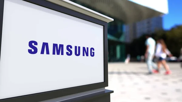 Oznakowanie ulicy deska z Samsung logo. Centrum biurowe niewyraźne i chodzenia osób tła. Redakcji renderowania 3d — Zdjęcie stockowe