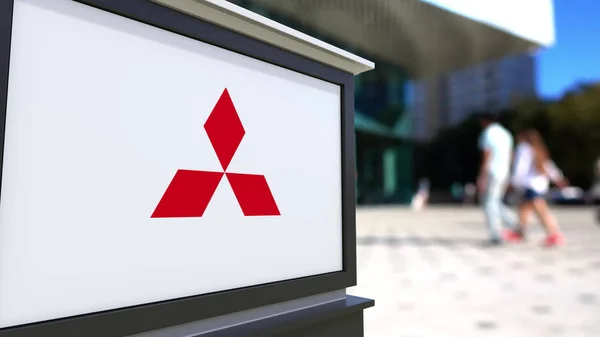 Street signage board with Mitsubishi logo. Blurred office center and walking people background. Editorial 3D rendering — Stock Photo, Image