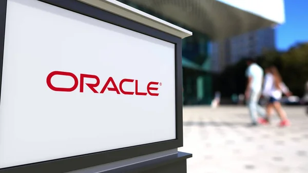 Tablero de señalización con el logotipo de Oracle Corporation. Centro de oficina borrosa y gente caminando fondo. Representación Editorial 3D —  Fotos de Stock
