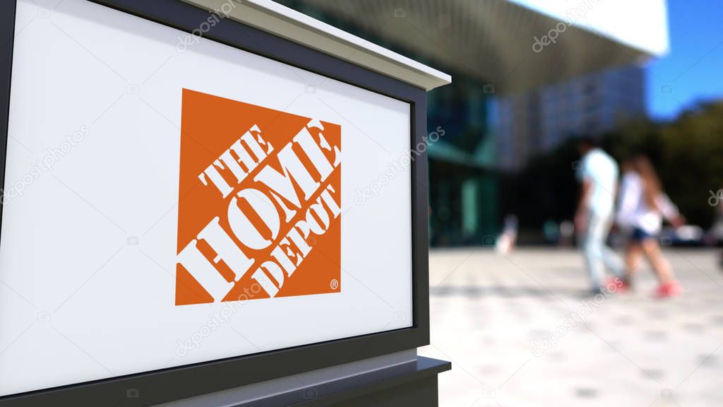 Street signage board with The Home Depot logo. Blurred office center and walking people background. Editorial 3D rendering United States