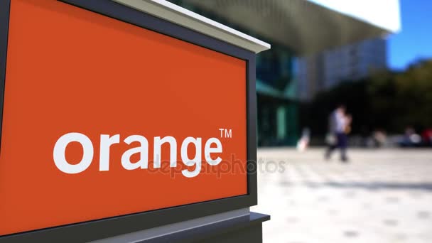 Уличная вывеска с логотипом Orange S.A. Размытый офисный центр и ходячий фон. 4K 3D-рендеринг — стоковое видео