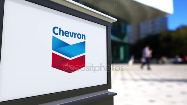 Pouliční nápisy deska s logem Chevron Corporation. Centrum rozmazané office a chodící lidé pozadí. Úvodník 4k 3d vykreslování — Stock video
