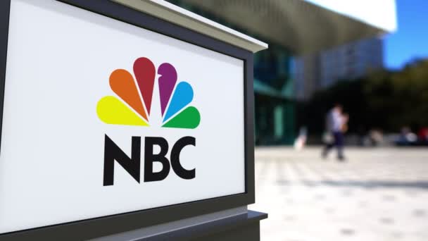 Panneau de signalisation routière avec logo NBC de la National Broadcasting Company. Centre de bureau flou et les gens de marche arrière-plan. Éditorial 4K rendu 3D — Video