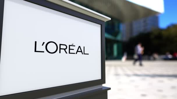 Placa de sinalização de rua com logotipo LOreal. Centro de escritórios desfocado e pessoas ambulantes fundo. Editorial 4K 3D renderização — Vídeo de Stock