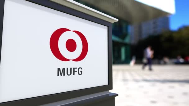 Straat signalisatie bord met Mufg logo. Wazig office center en wandelende mensen achtergrond. Redactioneel 4k 3D-rendering — Stockvideo