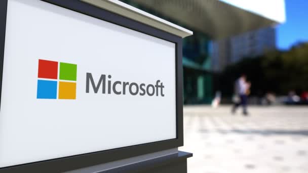 Tablero de señalización de calle con logotipo de Microsoft. Centro de oficina borrosa y gente caminando fondo. Representación editorial 4K 3D — Vídeos de Stock