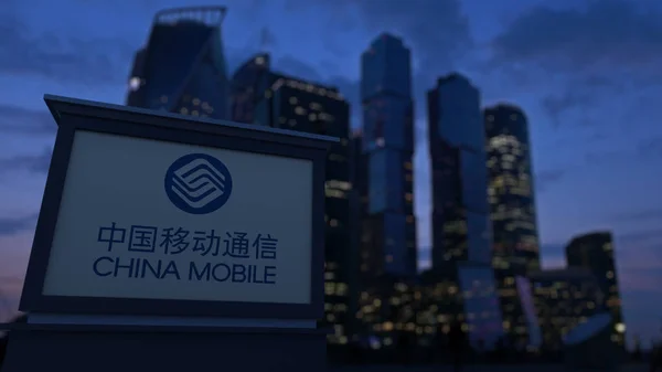 Straat signalisatie bord met China Mobile logo in de avond. Zakelijke district wolkenkrabbers achtergrond wazig. Redactioneel 3D-rendering — Stockfoto